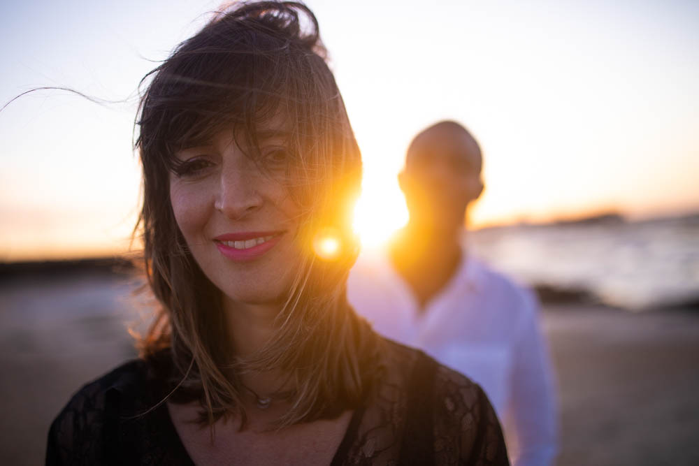 Los novios con el sol entre ellos durante fotografía de bodas en la playa de La Caleta de Cádiz